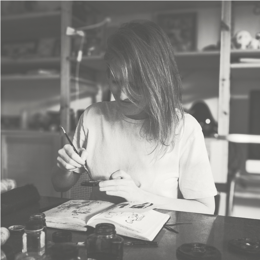 Photograph of Laura Quick sitting at her desk in her studio